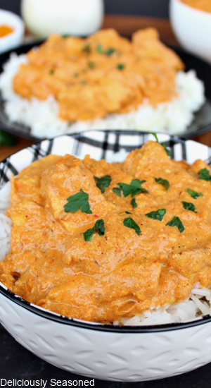 Butter Chicken in a white bowl, served over rice and topped with cilantro.