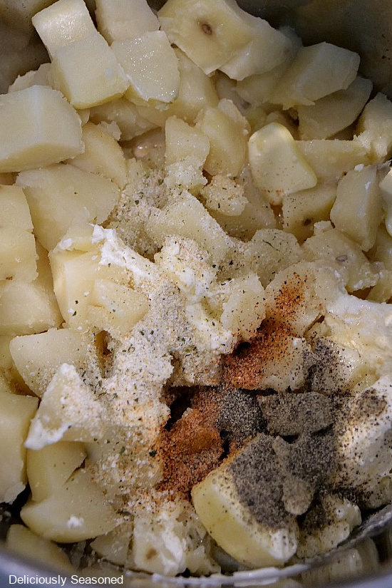Diced potatoes, salt, pepper, Cajon seasoning and butter in the instant pot before mixing together.