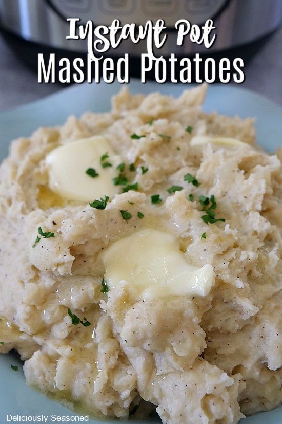 A light blue bowl with a serving of mashed potatoes with butter that has started to melt and parsley flakes.