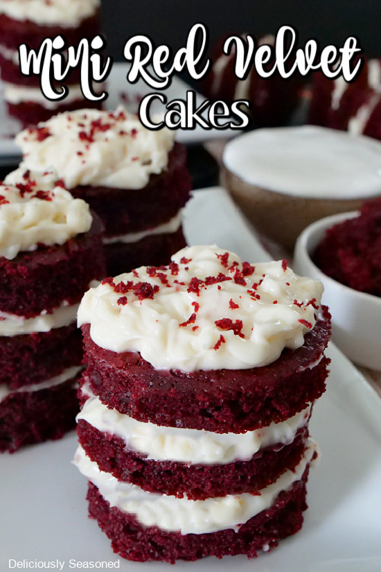 3 mini red velvet cakes on a white plate with cream cheese frosting in between the layers with cake crumbles on top of the frosting.