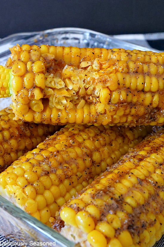 4 ears of Cajun buttered corn on the cob with one ear with a bite taken out.