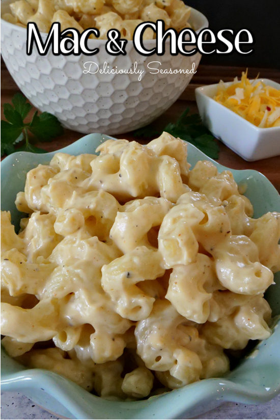 A teal bowl filled with mac and cheese with a white bowl in the background.