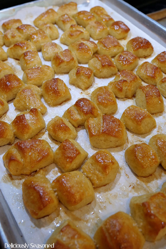 A picture showing the freshly baked Soft Pretzel Bites on a prepared baking sheet, brushed with melted butter and sprinkled with sea salt.
