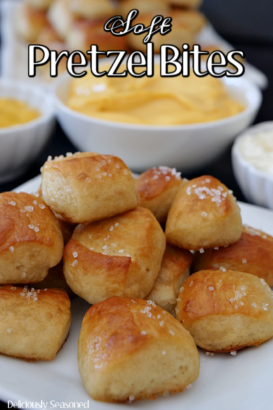 Soft Pretzel Bites covered with salt stacked up on a white plate with mustard in a small white bowl, nacho cheese in a larger white bowl, and cream cheese in a small white bowl in the background. The title is in the center at the top of picture. 