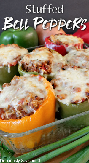 Stuffed bell peppers in a clear casserole dish, all with melted cheese on top.