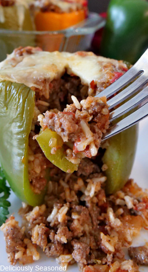 A stuffed bell pepper on a white plate, with a piece cut out of it and a bite on a fork.