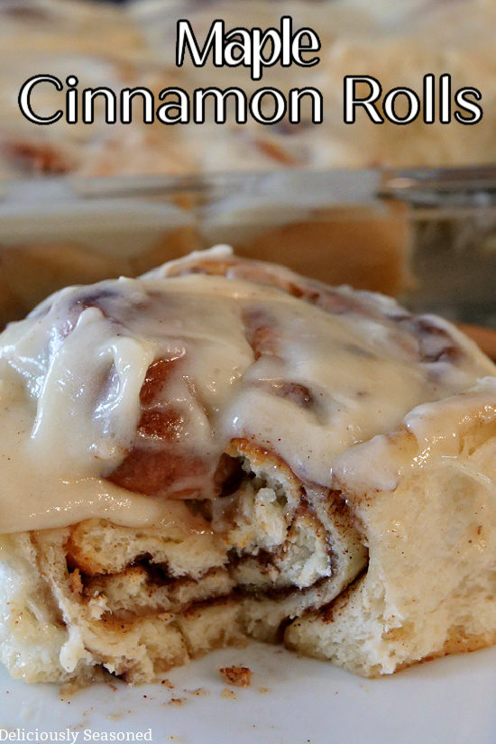 A close up photo of a maple cinnamon roll with a bite taken out showing the inside layers of the cinnamon roll.