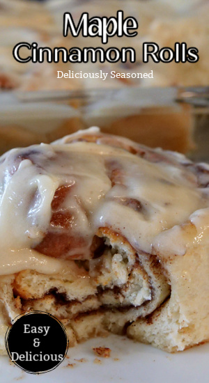 A close up photo of a cinnamon roll topped with icing and a bite taken out of it.