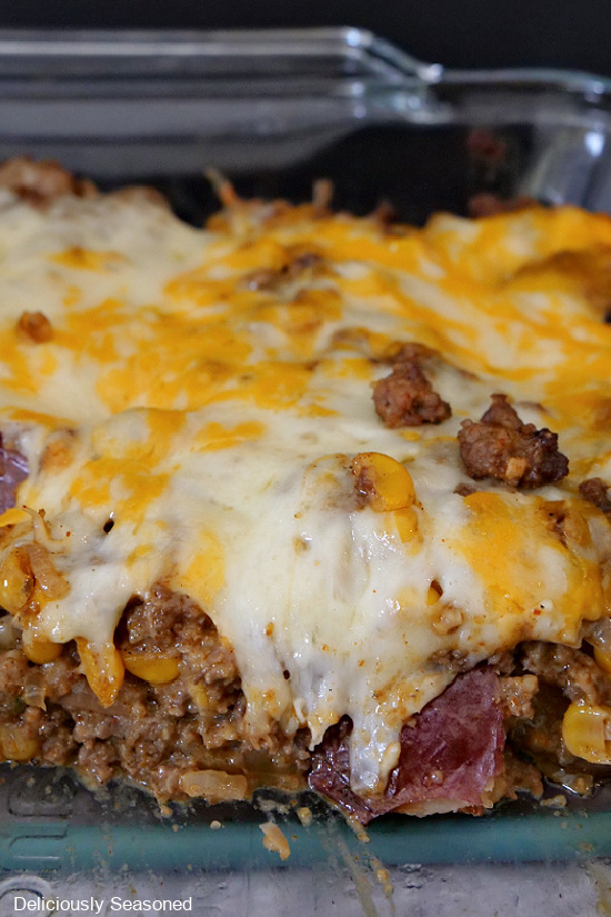 Loaded Roasted Potatoes in a glass baking dish showing the potatoes, ground beef and melted cheese.