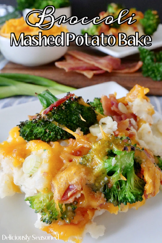 A white plate with broccoli mashed potato bake on it showing the mashed potatoes, melted cheese, broccoli florets and bacon with cheese and bacon in the background.