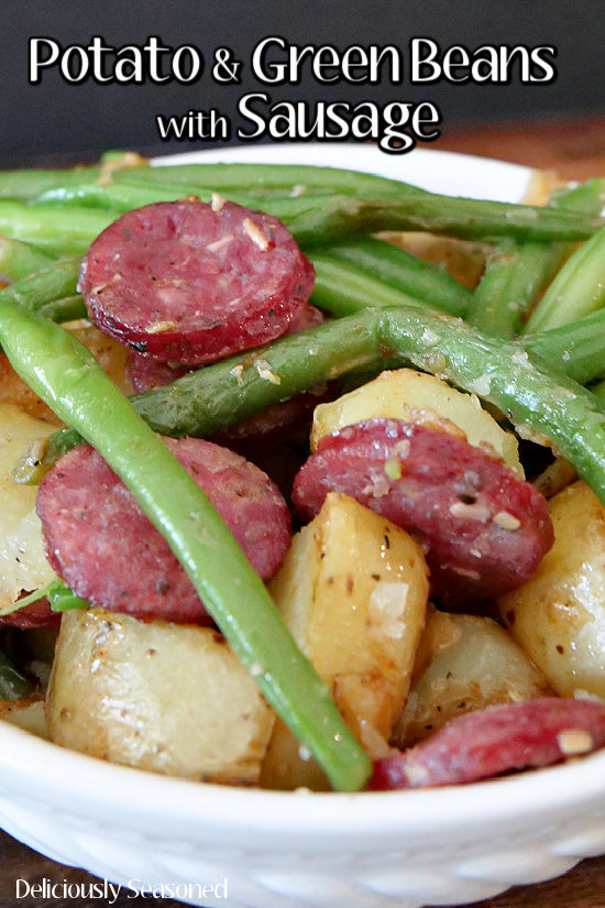 A white bowl filled with potatoes and green beans with sausage.
