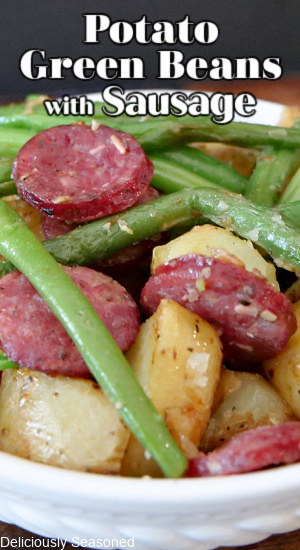 A white bowl filled with potatoes, green beans, and sausage.