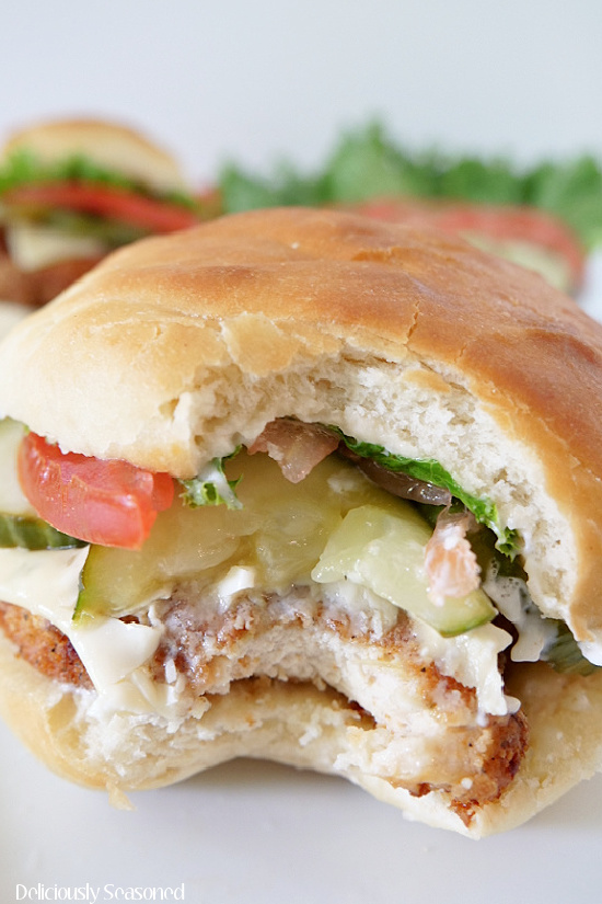 A close up picture of The Best Chicken Sandwich with a bit taken out of it, showcasing the tender and juicy inside of the crispy fried chicken breast.