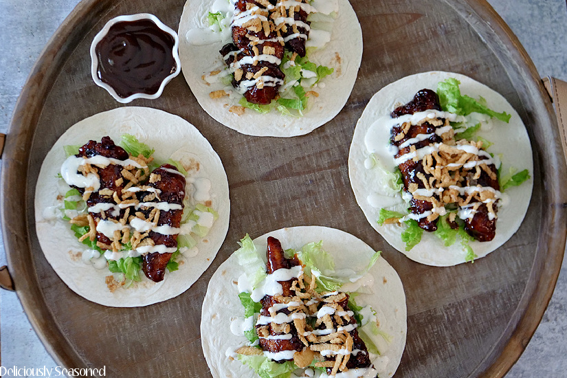 An overhead photo of flour tortillas with honey BBQ chicken, ranch, lettuce, and fried onions.
