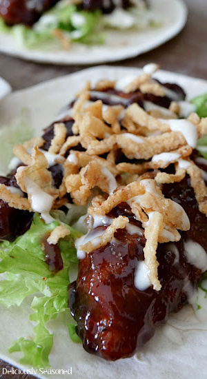 A flour tortilla topped with honey BBQ chicken, ranch dressing, lettuce, and fried onions.