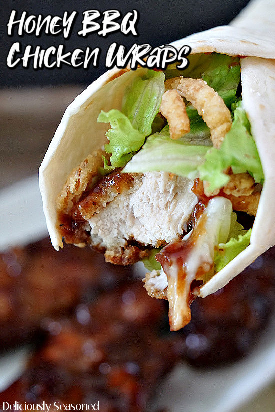 A close up photo of honey BBQ chicken in a flour tortilla with lettuce and fried onions.
