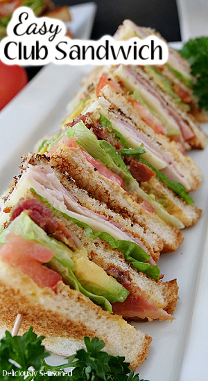 Club sandwiches cut in quarters, lined up on a white plate.