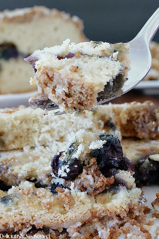 A super close up photo of a bite of Blueberry Streusel Cake on a fork.
