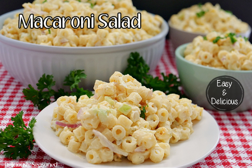 Macaroni Salad on a white plate with 3 more bowls in the background filled with macaroni salad.