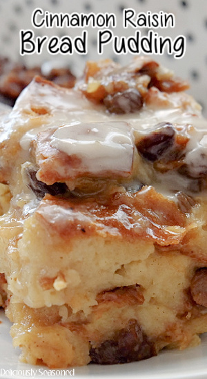 A close up photo of cinnamon raison bread pudding on a white plate, topped with a homemade glaze. 