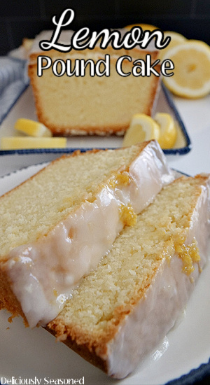 Two slices of lemon pound cake on a white plate with the loaf in the background surrounded by lemons.