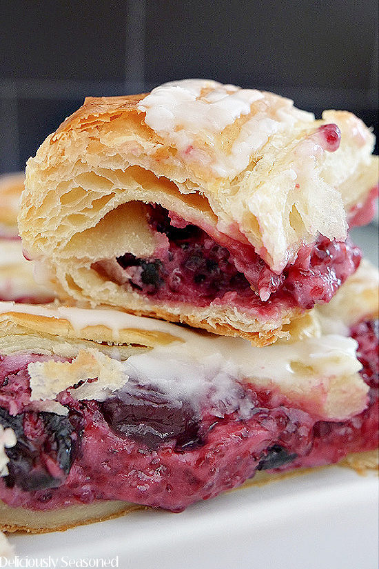 A super close up photo of two slices of Cherry Cream Cheese Danish stacked on top of each other showing the cream cheese and cherry filling.