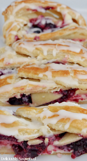 A photo of a Cherry Cream Cheese Danish right after it has been sliced and placed on a white plate.