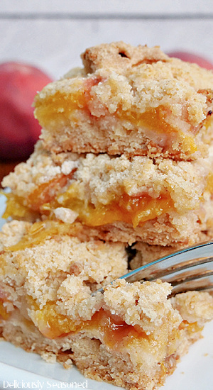 A close up of 3 peach crumb bars on a white plate.