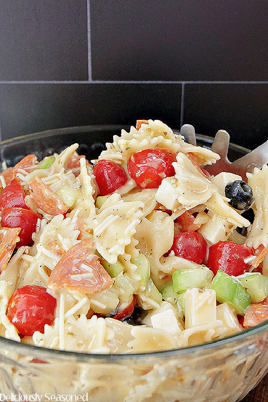 A glass bowl filled with Bow Tie Pasta Salad.