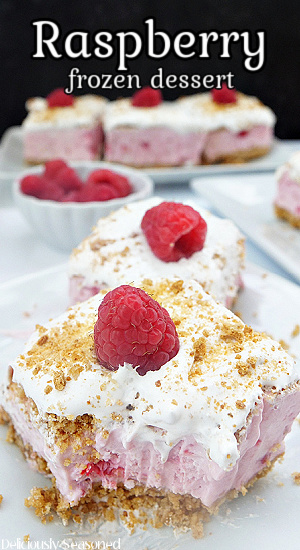 A photo of 5 slices of frozen raspberry desserts on white plates, topped with a raspberry, two in the front and three slices in the background with the title on the top of the recipe.