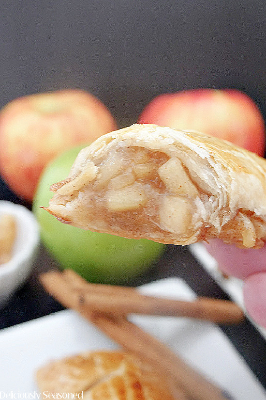 A close up photo of a apple cinnamon hand pie with a large bite taken out of it.