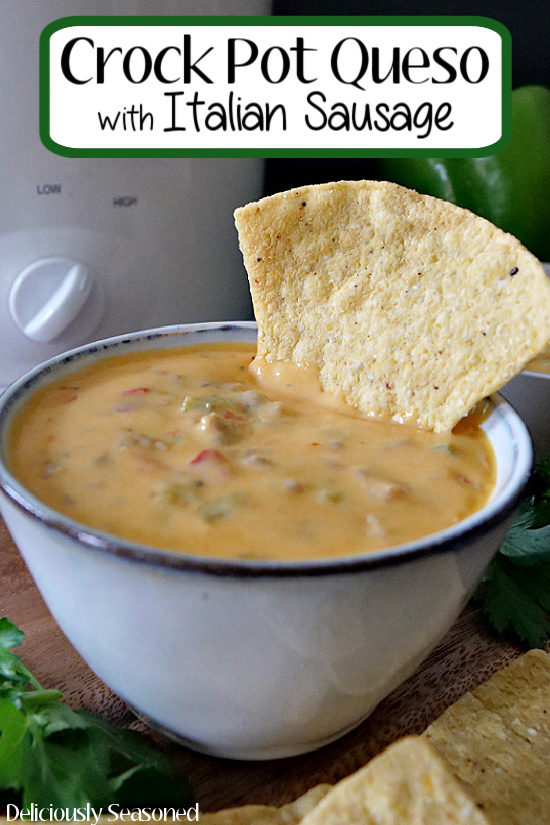 A grey bowl filled with crock pot queso with Italian sausage and a tortilla chip dipped in the bowl. Also, the title of the recipe is on the top of the photo.