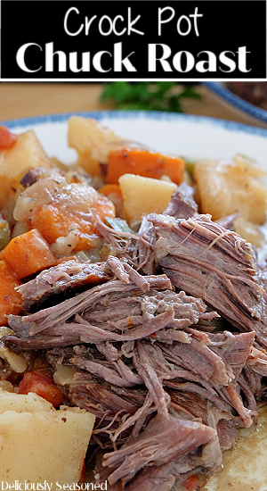 A close up photo of a piece of chuck roast with potatoes and carrots on a white plate with blue trim.