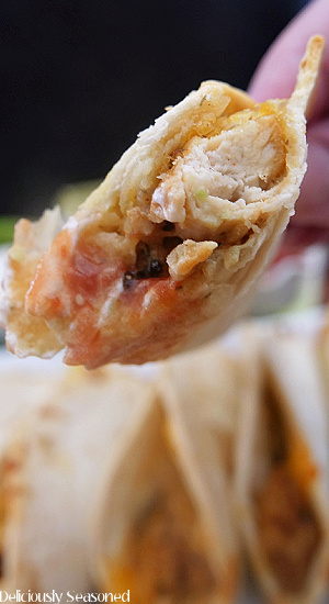 A super close up photo of a baked chicken taco that has a bite out of it.