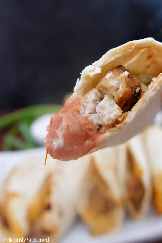 A super close up photo of a chicken taco with a bite out of it showing the inside ingredients.