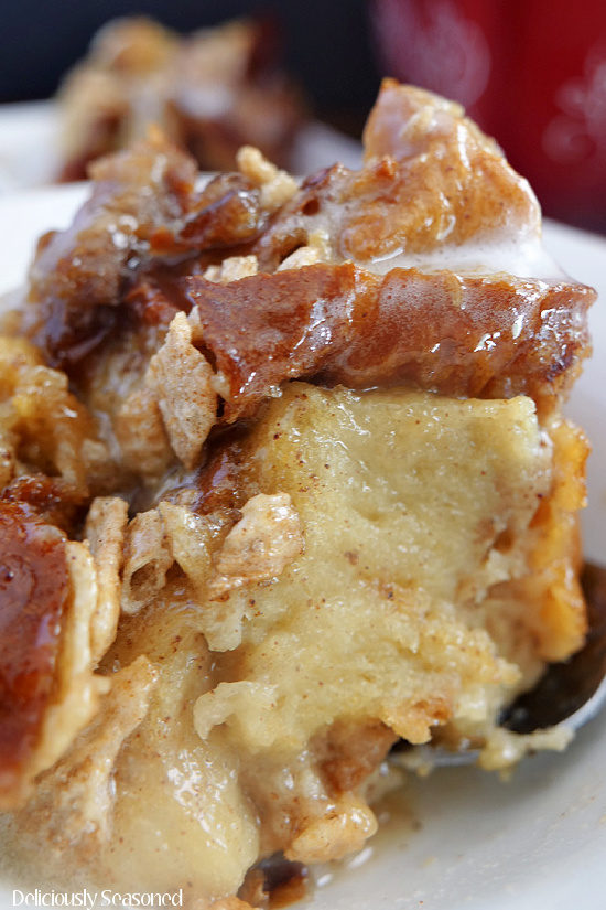 A close up photo of cinnamon toast crunch bread pudding on a white plate topped with a sweet glaze.