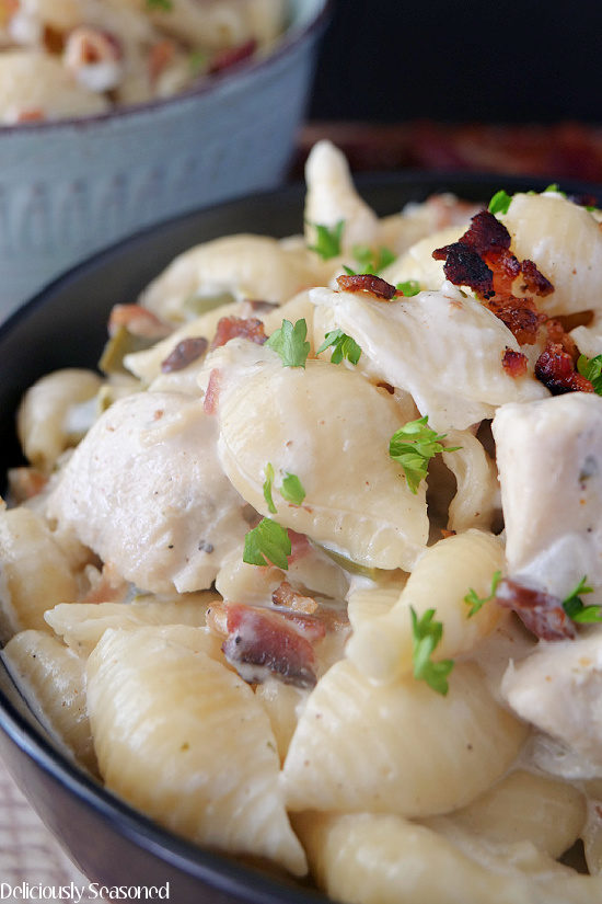 A close up photo of a black bowl with chicken bacon ranch pasta in it.
