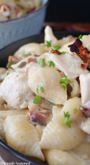 A close up photo of a black bowl filled with chicken bacon ranch pasta.