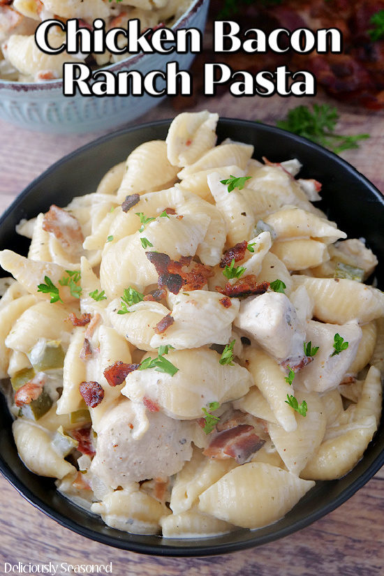 Chicken Bacon Ranch Pasta in a black bowl sitting on a wood surface with the title at the top of the photo.