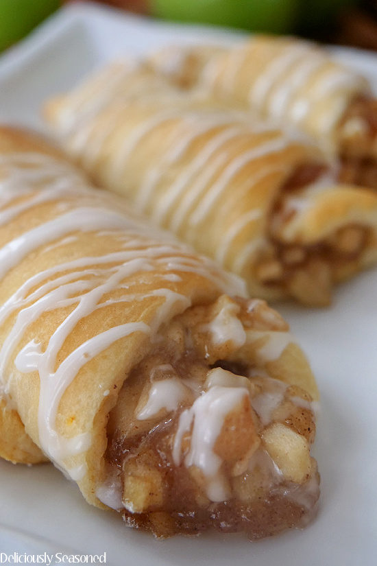A close up photo of three apple pie crescents on a white plate.