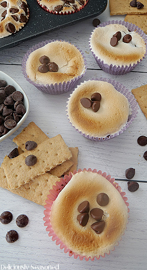 An overhead photo of easy s'more cups on a white board with chocolate chips and graham crackers scattered in between.