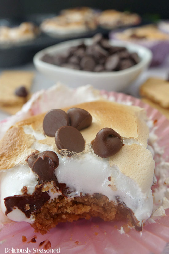A close of photo of a smores cup with a bite taken out of it, showing the graham cracker crust, marshmallow fluff, and melted chocolate chips.