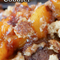 A white bowl filled with peach cobbler, topped with a delicious crumble topping.