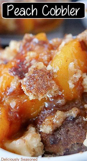 A super close up photo of a bowl of homemade peach cobbler with the title of the recipe on the photo.