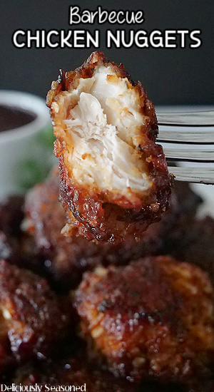 A close up photo of a barbecue chicken nugget on a fork with a bite taken out of it.