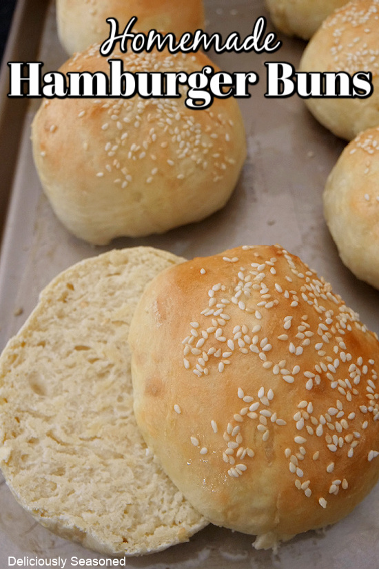A close up photo of a baking sheet with hamburger buns on it, all topped with sesame seeds.