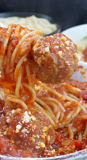 A white bowl filled with spaghetti and meatballs, covered in a homemade sauce.
