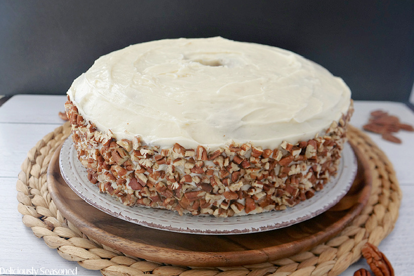 A full size butter pecan pound cake topped with a cream cheese frosting and the outside is covered in chopped pecans.