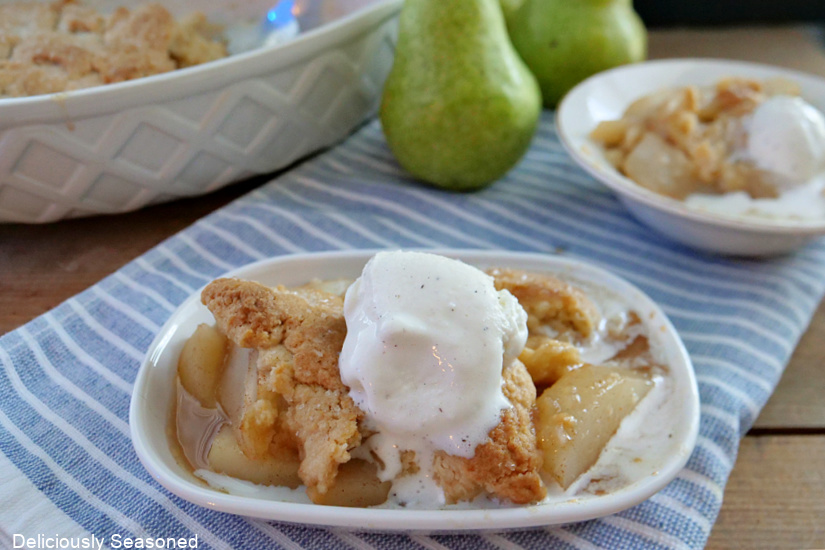 A white shallow bowl with a serving of easy pear cobbler and vanilla ice cream on top.