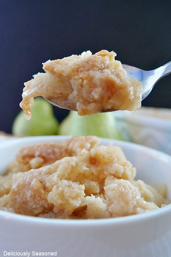 A close up photo of a spoonful of pear cobbler.